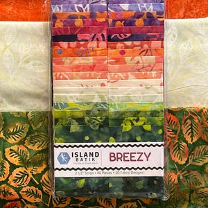 May include: A package of fabric strips in a variety of colors, including purple, orange, green, and white. The package is labeled "BREEZY" and contains 2 1/2" strips. The fabric has leaf and floral patterns.