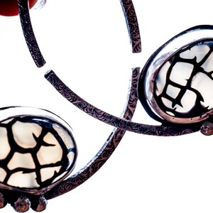 May include: A pair of silver hoop earrings with a white agate stone set in each hoop. The agate stones have a black dendritic pattern.