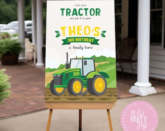May include: A wooden easel displays a colorful birthday sign. The sign features a green tractor illustration with the text "START YOUR TRACTOR and put it in gear" and "THEO'S 3RD BIRTHDAY is finally here!" The sign is set against a backdrop of a green field.