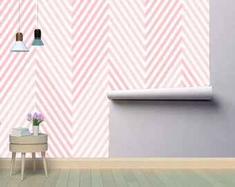 May include: Pink and white chevron patterned wallpaper roll with a white backing. The wallpaper is rolled up and partially unrolled, showing the pattern. The wallpaper is in a room with a small table and a wooden floor.