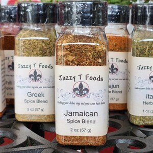May include: Several glass spice jars with black lids, each labelled with a different spice blend name. The labels feature the "Jazzy T Foods" logo and include the weight of the contents in grams. The jars are filled with various herbs and spices.