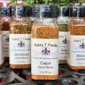 May include: A selection of spice blends in clear glass jars with black lids. Each jar features a label with the "Jazzy T Foods" logo and the spice blend name, including "Cajun" and "Mexican". Each jar contains 57 grams of spice.