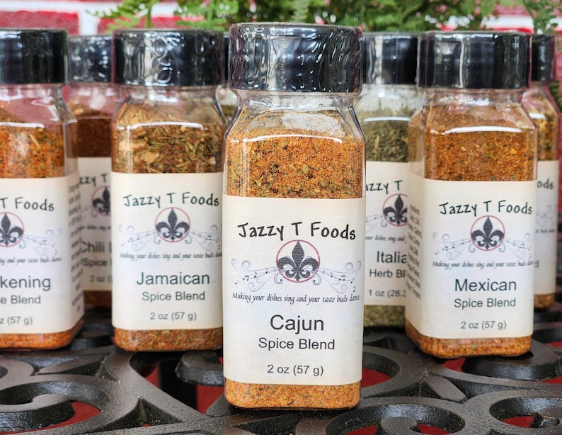 May include: A selection of spice blends in clear glass jars with black lids. Each jar features a label with the "Jazzy T Foods" logo and the spice blend name, including "Cajun" and "Mexican". Each jar contains 57 grams of spice.
