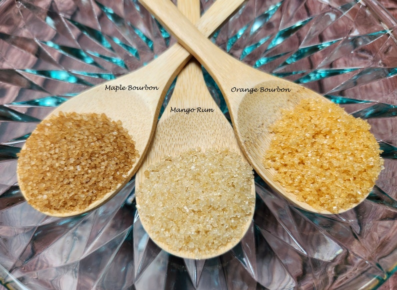 May include: Three wooden spoons filled with brown sugar. The spoons are labeled "Maple Bourbon", "Mango Rum", and "Orange Bourbon".