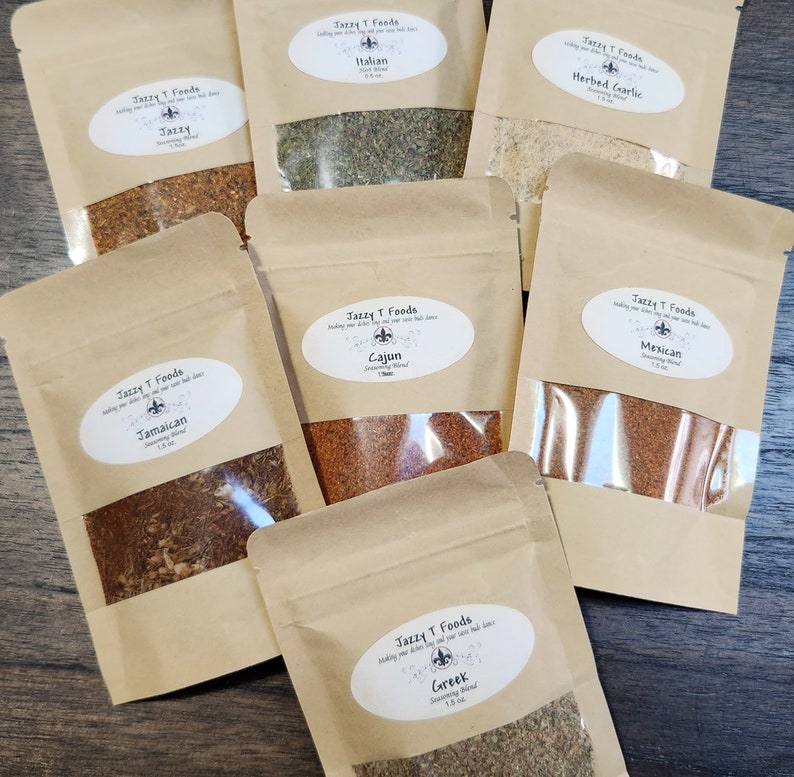 May include: Seven small brown paper bags with clear plastic windows, each containing a different spice blend. The bags are labelled with the name of the blend, "Jazzy T Foods", and the size, 1.5 oz. The blends are: Jamaican, Cajun, Mexican, Italian, Herbed Garlic, Jazzy, and Greek.
