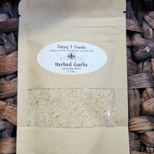 May include: A brown paper pouch with a white label that reads "Jazzy T Foods Making your dishes sing and your taste buds dance Herbed Garlic Seasoning Blend 1.5 oz."