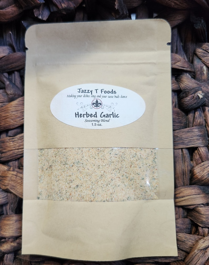 May include: A brown paper pouch with a white label that reads "Jazzy T Foods Making your dishes sing and your taste buds dance Herbed Garlic Seasoning Blend 1.5 oz."