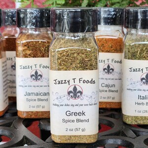 May include: A selection of spice blends in clear glass jars with black lids. Labels display "Jazzy T Foods" and various blends, including Greek, Italian, and Cajun. Each jar contains 57 g of spice, except the Italian blend, which contains 28.35 g.