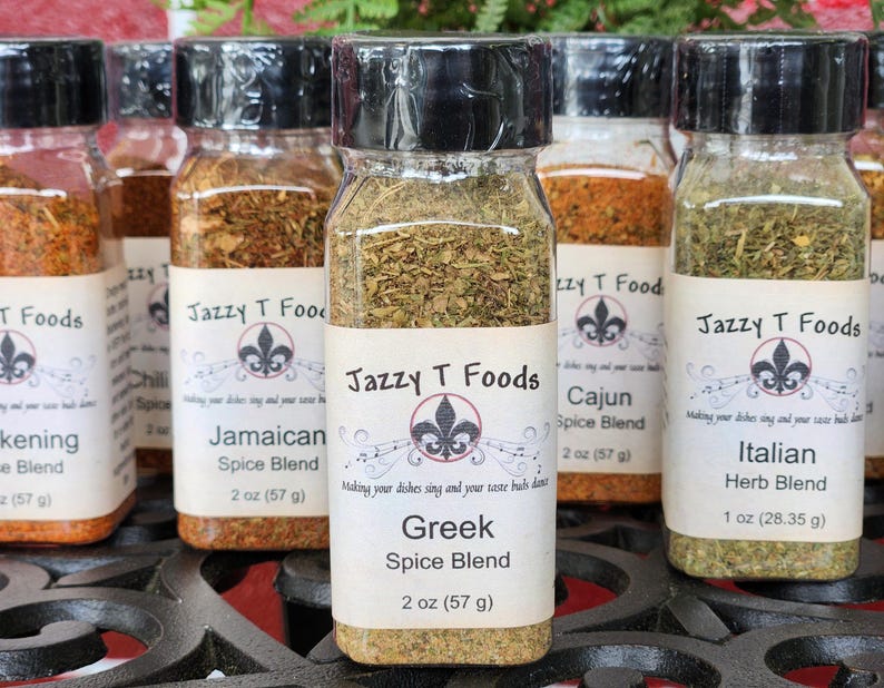 May include: A selection of spice blends in clear glass jars with black lids. Labels display "Jazzy T Foods" and various blends, including Greek, Italian, and Cajun. Each jar contains 57 g of spice, except the Italian blend, which contains 28.35 g.
