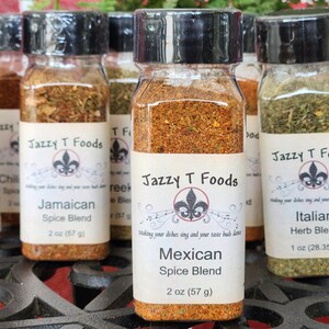 May include: Several glass spice jars with black lids, each labelled with a different spice blend name. The labels feature the "Jazzy T Foods" logo and include the spice blend name and weight in ounces and grams.