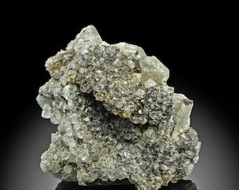 Pode incluir: Uma imagem em close-up de um espécime mineral com um aglomerado de pequenos cristais translúcidos e opacos. Os cristais são principalmente cinza e transparentes, com uma superfície áspera e texturizada. O fundo é preto.