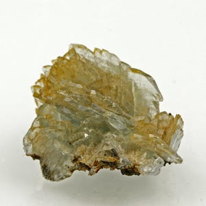 Può includere: Un campione di minerale traslucido e stratificato con una tavolozza di colori giallo chiaro e trasparente. La struttura cristallina ha un aspetto a ventaglio, con più strati e una consistenza ruvida. La base del campione è di colore marrone scuro.