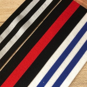 May include: Three different striped elastic bands. One is black and white, one is red and black, and one is blue and white.