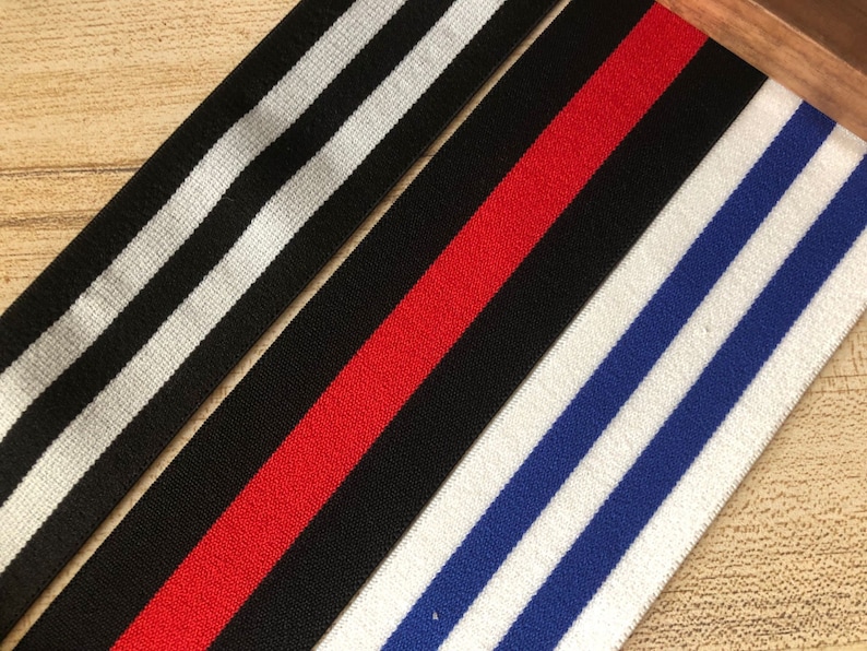 May include: Three different striped elastic bands. One is black and white, one is red and black, and one is blue and white.