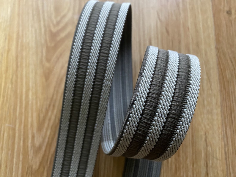 May include: Brown and white striped woven trim with a textured surface. The trim is approximately 1 inch wide.