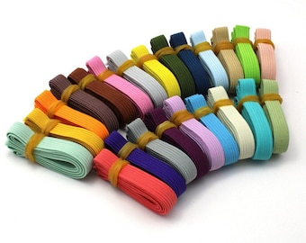 May include: A collection of 24 colorful elastic bands, each rolled up and secured with a rubber band. The bands are in various shades of blue, green, pink, purple, orange, yellow, brown, and white.