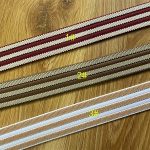 May include: Three different types of elastic trim with two white stripes on a brown background. The trim is shown on a wooden surface. The trim is labeled 1#, 2#, and 3#.