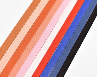 May include: Assortment of eight different colored elastic bands, each with a subtle ribbed texture. The colors are black, navy blue, red, orange, pink, white, light peach, and beige.