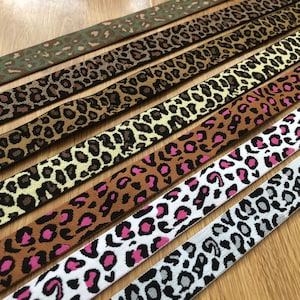 May include: Assortment of leopard print elastic bands in various colors, including brown, black, white, pink, and green.