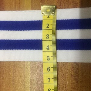 May include: White and blue striped elastic trim with a yellow measuring tape showing 9 inches.