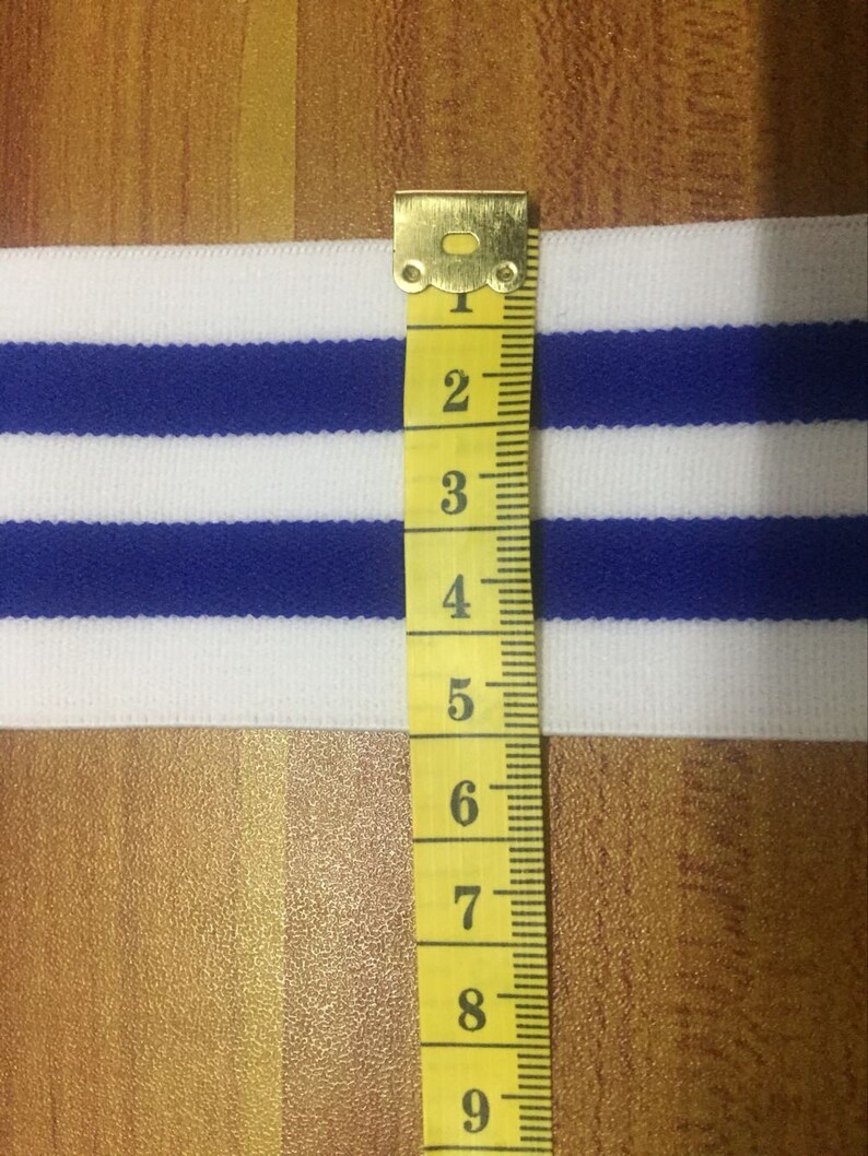 May include: White and blue striped elastic trim with a yellow measuring tape showing 9 inches.