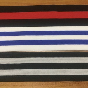 May include: Three different types of elastic trim with striped patterns. The first trim is black with a red stripe. The second trim is white with blue stripes. The third trim is black with gray stripes.