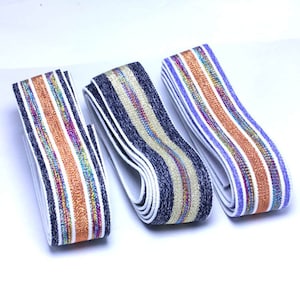 May include: Three rolls of elastic trim with white, blue, and purple stripes. The stripes have a metallic gold thread woven into them.