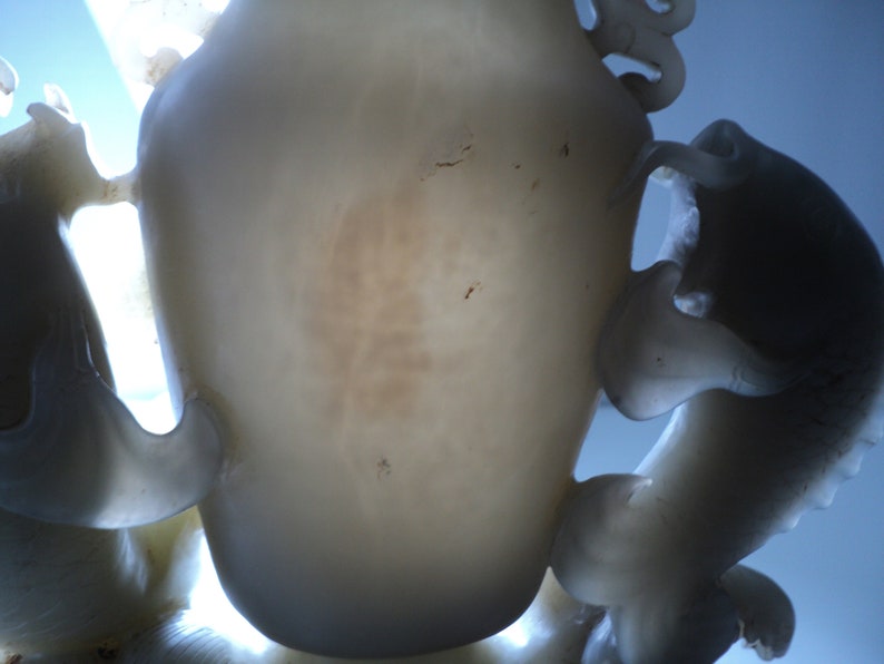May include: A white jade sculpture of a dragon with intricate details. The dragon is curled up with its head raised and its tail curled around its body. The sculpture is made of a translucent white jade with a slight brown tint.