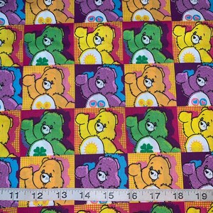 May include: A colorful fabric with a repeating pattern of Care Bears. Each bear is wearing a different colored shirt and has a different symbol on their belly. The fabric is yellow, pink, purple, green, and blue.