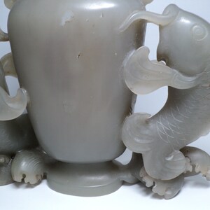 May include: A gray jade vase with two dragon handles. The vase is carved with intricate details and has a smooth, polished finish.