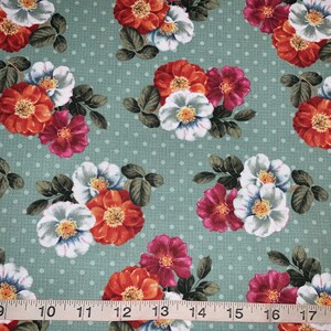 May include: A green fabric with a white polka dot pattern and a repeating floral design. The flowers are red, white, and pink.
