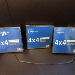 May include: Three 4x4 black finish front loading picture frames with easels included, in blue packaging. The frames are from Mainstays.