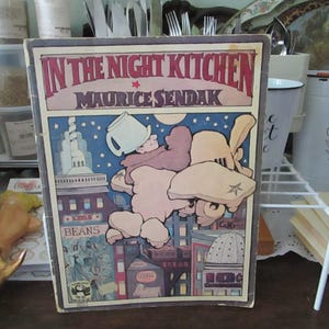 May include: A vintage children's book titled "In the Night Kitchen" by Maurice Sendak. The cover features a colorful illustration of a boy in a nightgown flying through the air with a loaf of bread.