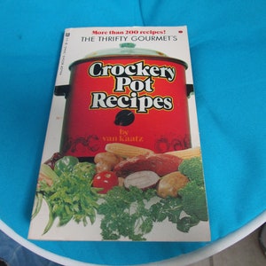 May include: A red Crockery Pot cookbook with the title "Crockery Pot Recipes" and the author "by van Kaatz". The cover features a close-up of a Crockery Pot with various vegetables and meat.