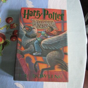May include: A hardcover book titled "Harry Potter and the Prisoner of Azkaban" by J.K. Rowling. The cover features an illustration of Harry Potter flying on a hippogriff.