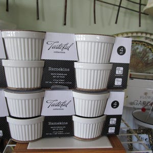 K&ouml;nnte beinhalten: Ein Set aus vier wei&szlig;en Porzellan-Ramekins, jedes mit einem geriffelten Design. Die Ramekins sind in einer schwarz-wei&szlig;en Schachtel verpackt, auf der "Tasteful collection" und "Ramekins" steht. Die Schachtel enth&auml;lt auch den Text "4 St." und "Wei&szlig;es Porzellan-Set mit vier Teilen".