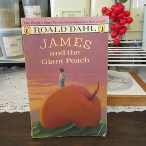 May include: A paperback book titled "James and the Giant Peach" by Roald Dahl. The cover features a colorful illustration of a giant peach with a small boy standing on top.