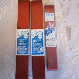 May include: Three spools of ribbon in shades of red. Two spools are labeled "Creative Craft & Floral Ribbons" and the third is labeled "Single-Face Satin". The ribbon is 1.8m x 15mm.