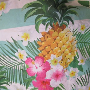 May include: A tropical print fabric with a pineapple, hibiscus flowers, and frangipani flowers in shades of pink, yellow, and white on a light blue and white striped background.