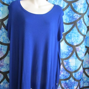 May include: A royal blue, short-sleeved, loose-fitting,  t-shirt with a round neckline. The shirt has a slightly longer length in the back.