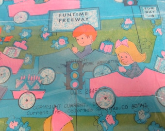 May include: A colorful wrapping paper design featuring a blue and pink car with a traffic light, a girl and boy in cars, and the text "Funtime Freeway".