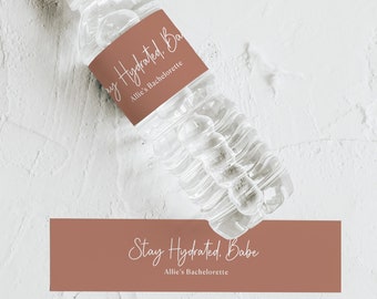 Puede incluir: Una etiqueta de botella de agua marrón y blanca con el texto "Stay Hydrated. Babe" y "Allie's Bachelorette".