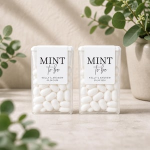 Puede incluir: Dos cajas de plástico transparente llenas de mentas blancas. Cada caja tiene una etiqueta blanca que dice "MINT to be" con los nombres "KELLY & ANDREW" y la fecha "09.26.2026". Son recuerdos de boda.