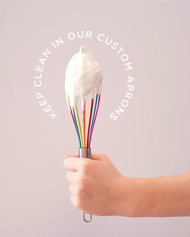 May include: A hand holding a rainbow-colored whisk with white whipped cream on the end. The text "Keep clean in our custom aprons" is written in a circle around the whisk.