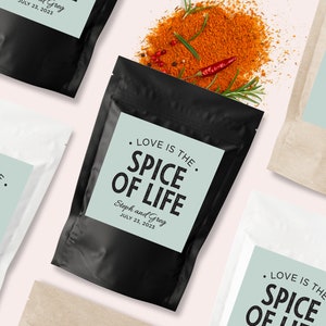 Puede incluir: Un conjunto de tres bolsas de especias con etiquetas que dicen "Love is the spice of life" con los nombres Steph y Greg y la fecha 23 de julio de 2023. Las bolsas son negras, blancas y marrones.