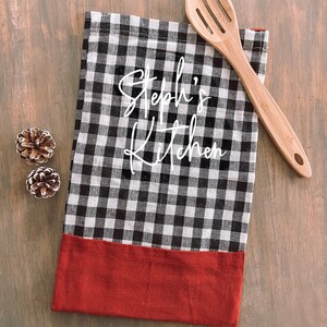 May include: Black and white checkered kitchen towel with a red border. The towel has the text "Steph's Kitchen" written in white cursive.