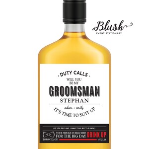 May include: A white label with black text on a clear glass bottle of liquor. The label reads "Duty Calls. Will you be my groomsman Stephan adam + emily It's time to suit up (If you decline, I want this bottle back) Your service is required for the big day Drink Up Toronto, ON 07.21.18".