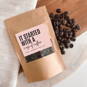 K&ouml;nnte beinhalten: Ein brauner Papierbeutel mit einem rosa Etikett, auf dem "It started with a cup of coffee" und "Lisa + Kenny 10.21.23" steht. Der Beutel ist mit Kaffeebohnen gef&uuml;llt.