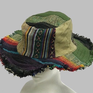 May include: A multi-coloured patchwork hat with a frayed brim. The hat is made of different fabrics, including a green canvas, a beige canvas, and a striped fabric with red, orange, yellow, blue, and green stripes. The hat has a wide brim and a flat crown.