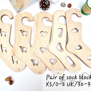 Op de afbeelding: Set van vijf houten sokkenspanners met verschillende ontwerpen, waaronder lama's, schapen, harten en wolken. De spanner zijn voor maat XS/0-2 UK/32-34 EU.